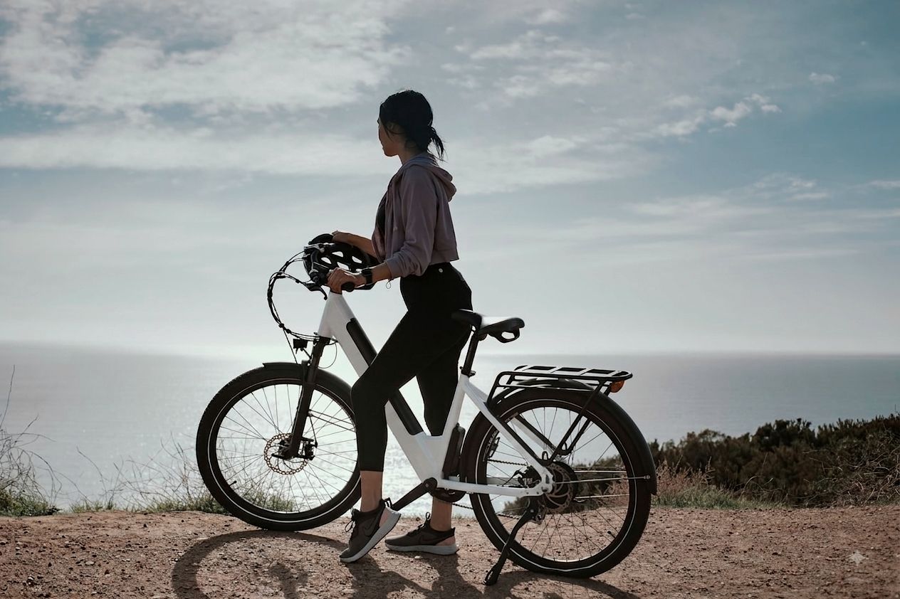 A rider pausing with an electric bike above the coast